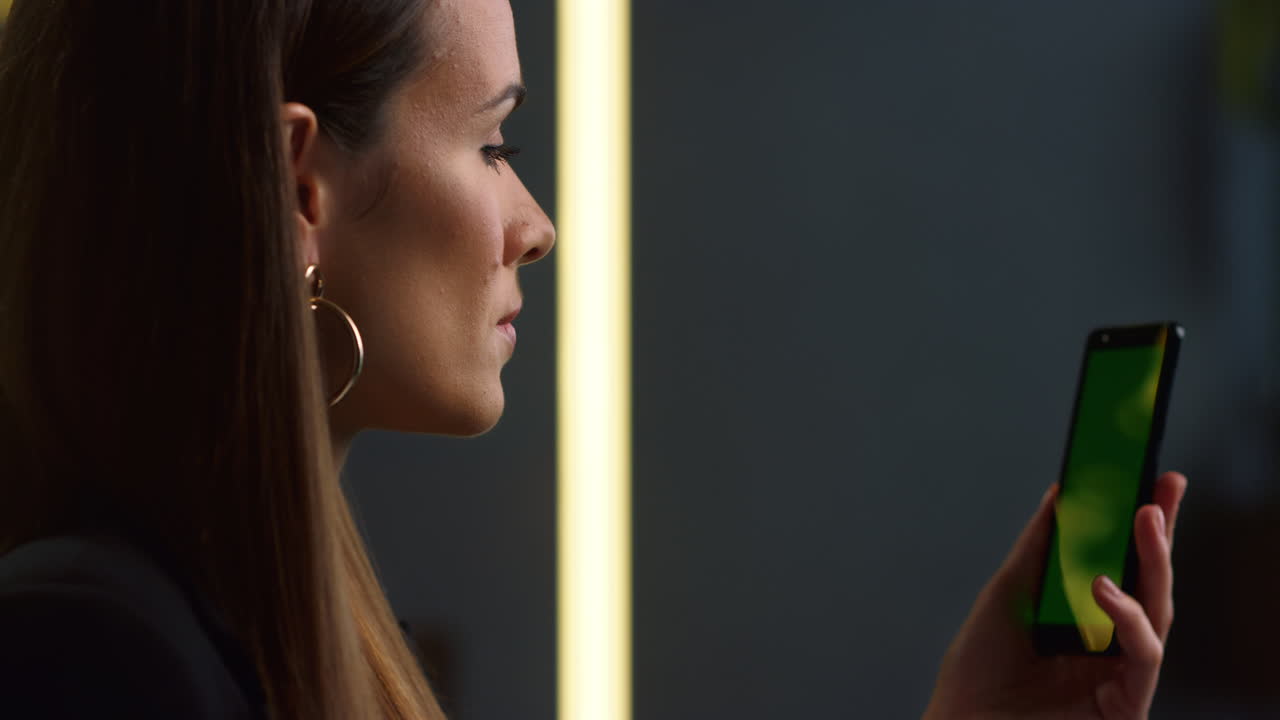 mujer de negocios enfocada que usa un teléfono móvil para hacer una videollamada en un lugar de trabajo remoto