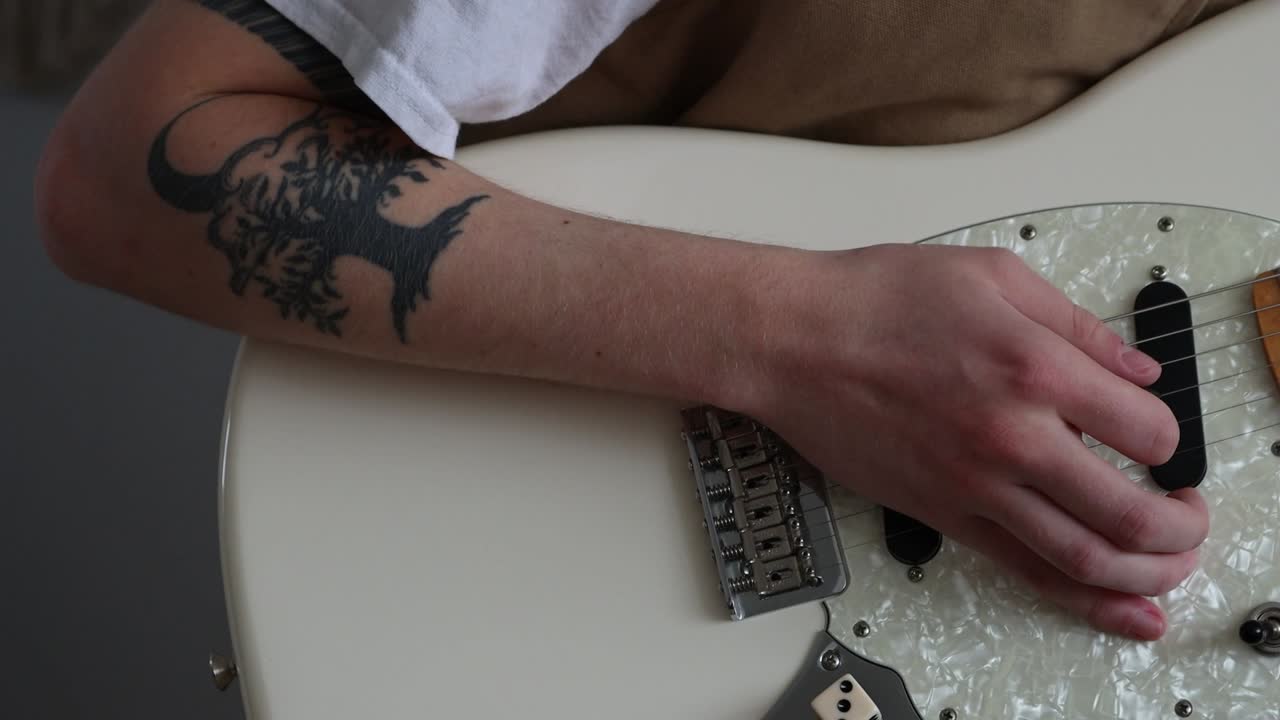 Una persona sta usando un plettro per strimpellare le corde di una chitarra elettrica.