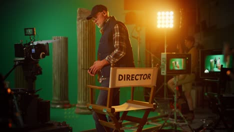prominente director sénior de éxito tiene lugar en su silla y ordena "acción!" para comenzar el rodaje. en el set de la película de estudio con equipos de alta gama equipo profesional de rodaje de película de alto presupuesto