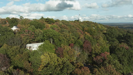 Volando-Sobre-Bosques-Otoñales-Con-Torre-De-Tanque-De-Agua-Al-Fondo-En-Fayetteville,-Mount-Sequoyah,-Arkansas,-Estados-Unidos