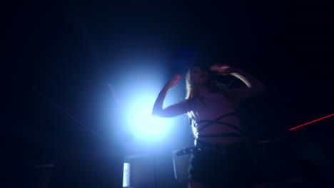 long-haired female dancer moving quickly in front of camera. rhythmic dancing in the dark room. low angle view.