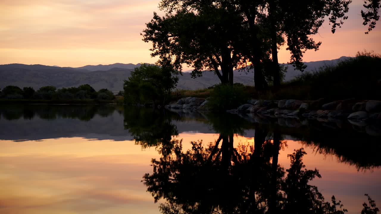 Time-lapse do pôr do sol e reflexo das árvores na superfície do lago.