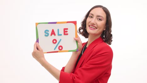 woman in a red blazer showing a 'sale' sign, expressing excitement for discounts