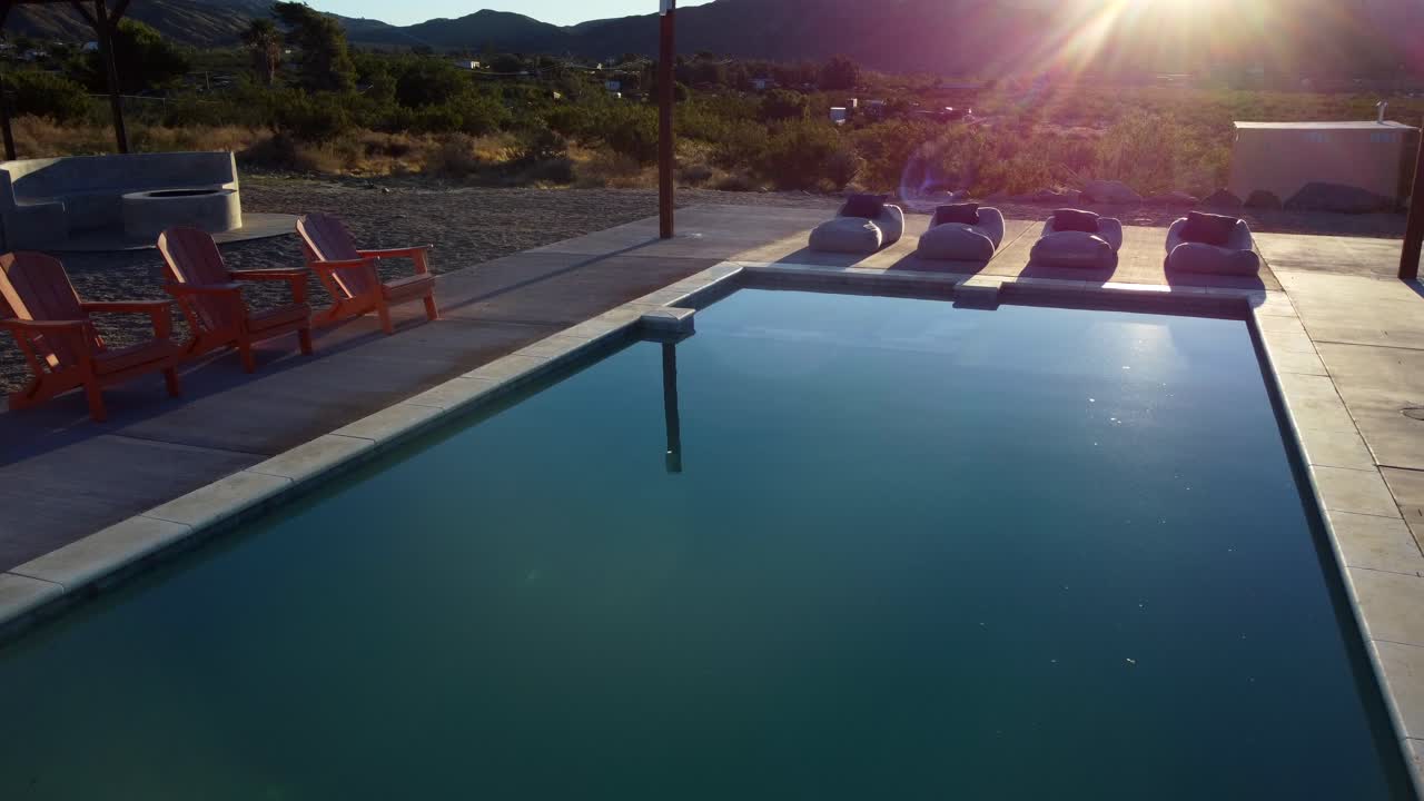 Drone flyver over swimmingpool ved solnedgang på et afslappende feriested.