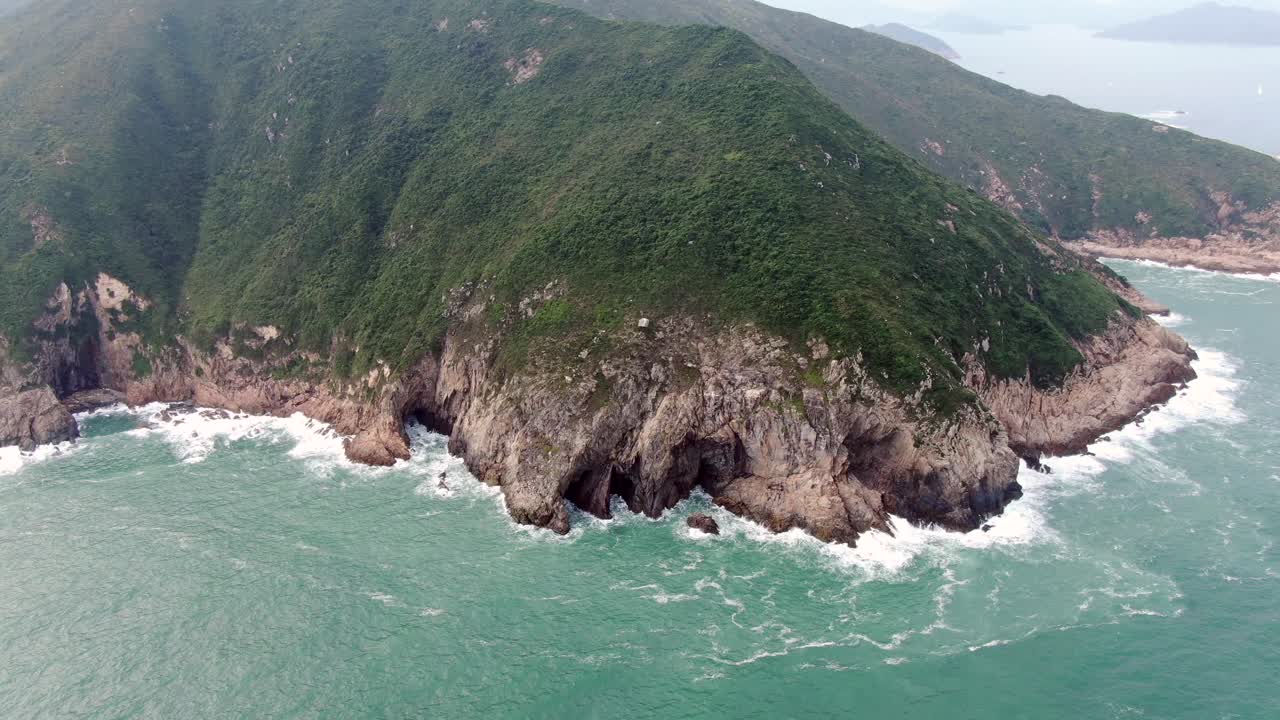 vista aérea de una isla rocosa irregular, rodeada de naturaleza verde y exuberante y agua de la bahía de hong kong