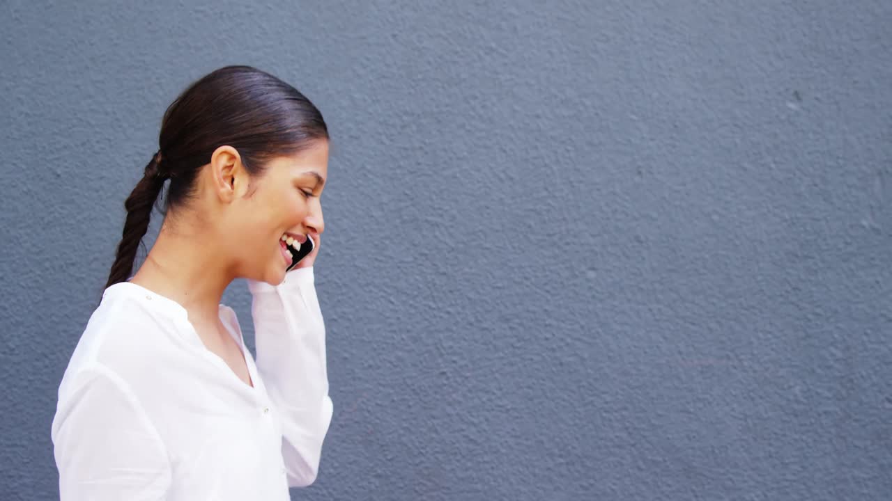 회색 벽 배경으로 전화를 하는 여자