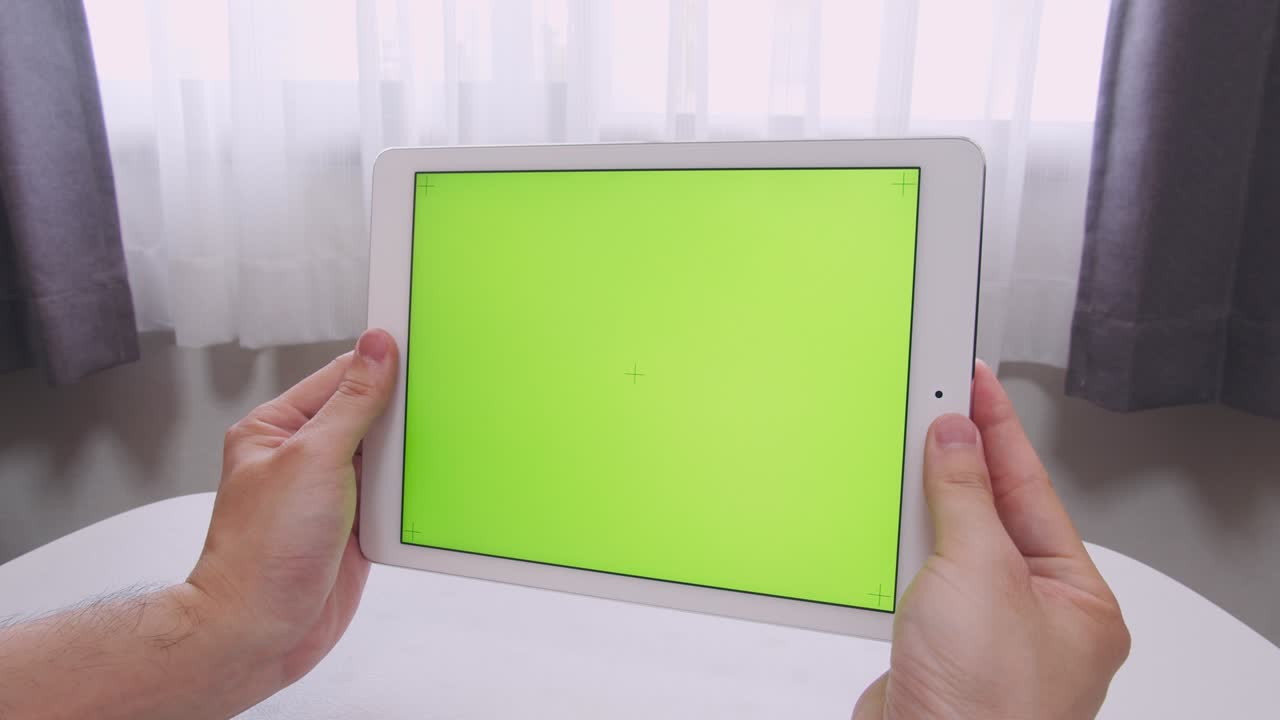 hombre con las manos sosteniendo una pantalla verde (clave de croma) tableta inteligente en su habitación