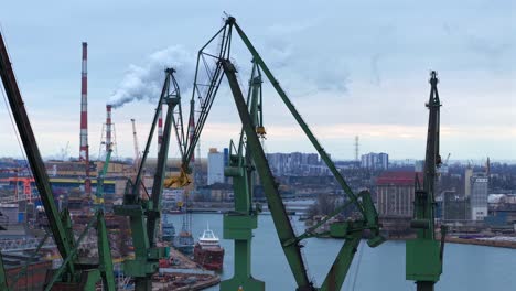 aerial shot over gdansk shipyard showing cranes, ships, and a coal heat plant