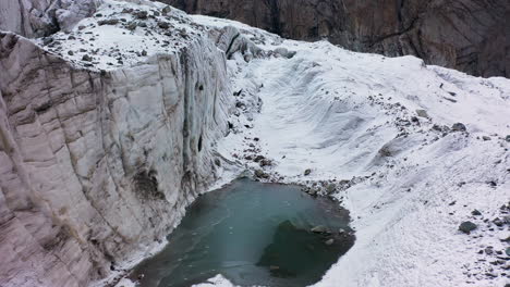 cinematic drone shot of a ravine and small lake in the ak-sai glacier in kyrgyzstan