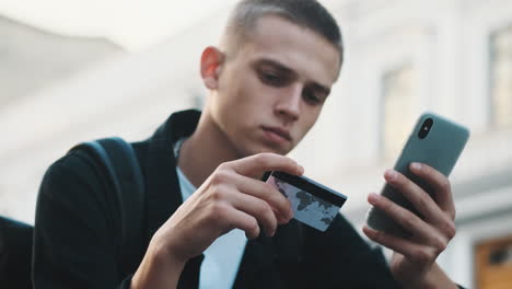 young student guy paying online with credit card.