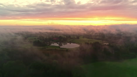 cloud inversion at sunrise over verdant landscape - bright yellow horizon, drone