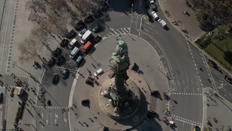 aerial: primer plano del monumento a colón en barcelona, españa en un hermoso día soleado con mucho tráfico de automóviles en la rotonda [4k]