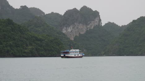 old cruise ship passing on karst mountains in ha long bay, northeast vietnam