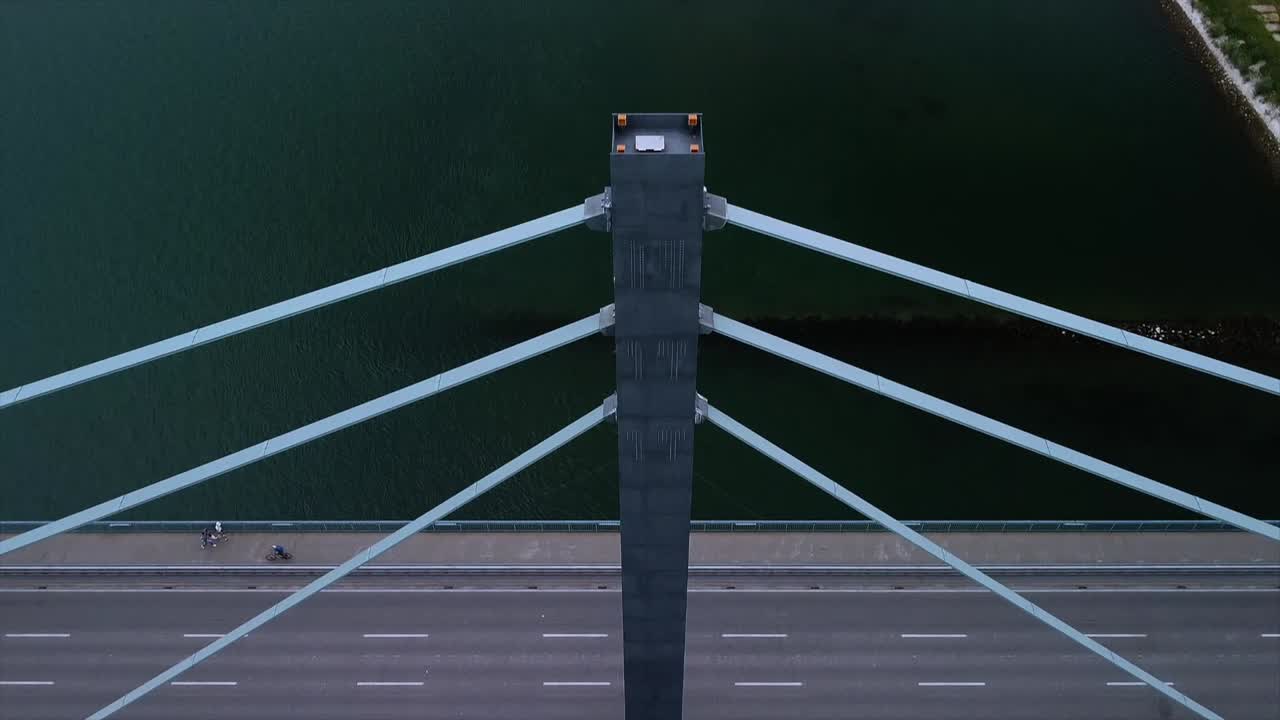 Drone camera shifting down from a beautiful River scenario onto passing cars on a important bridge in Germany