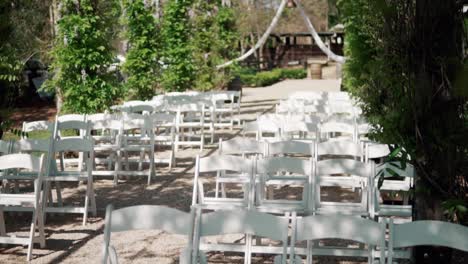 rows of white folding empty chairs before ceremony - outdoor wedding scene - static shot