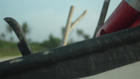 Close-up-of-a-stranded-boat-with-blurry-greenery-and-beach-in-the-background