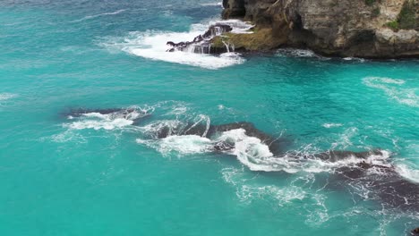 Agua-Tropical-Turquesa-Chocando-Contra-Rocas-Dentadas-En-La-Laguna-Azul-En-La-Isla-De-Nusa-Ceningan,-Antena