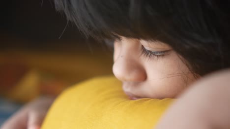 primer plano de una niña descansando la cabeza sobre una almohada amarilla