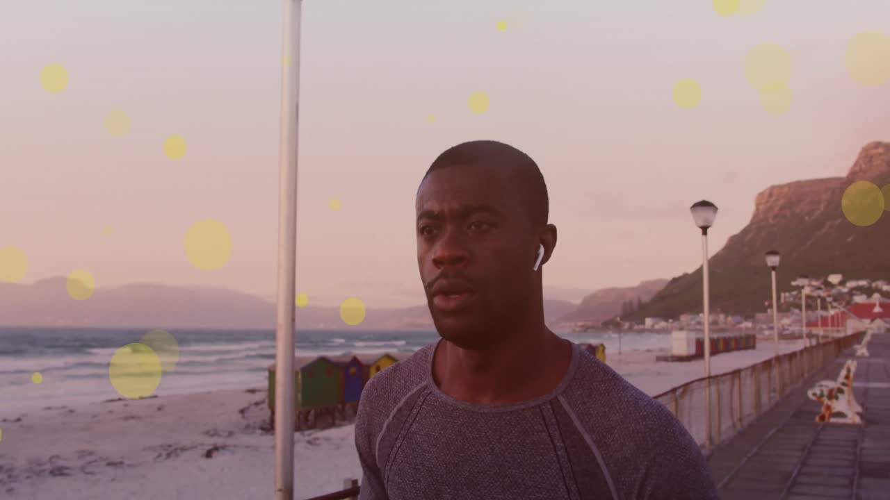 Yellow spots floating against african american fit man running on the promenade