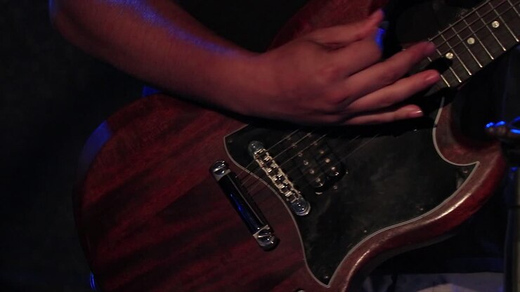 Canlı bir konserde sahnede gitar çalan gitarist.
