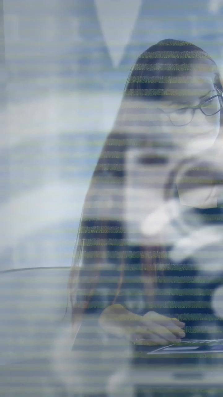 Vertical video: Seated woman editing on tablet in office while bands and rings drifting over face