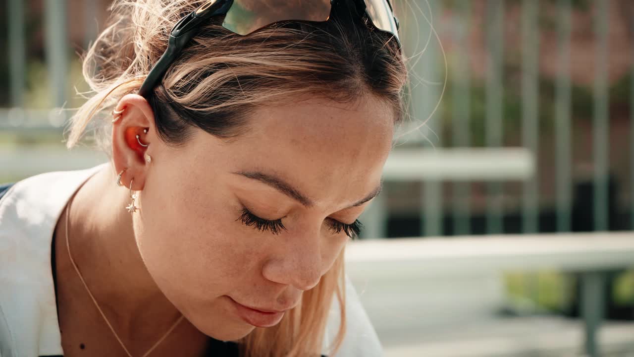 la atleta femenina mira intensamente hacia abajo mientras se ata los zapatos mientras se sienta en una fila de gradas