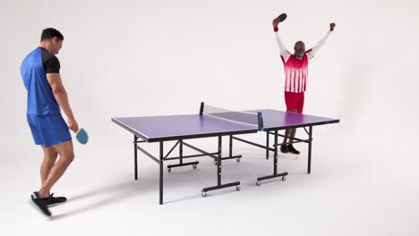 playing table tennis, two men celebrating and enjoying game in studio