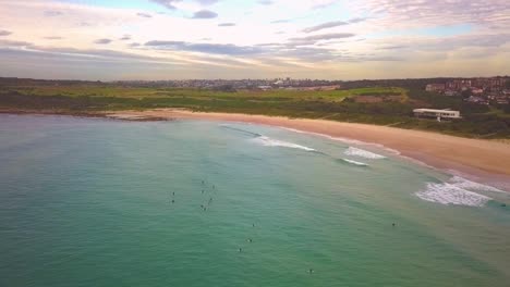 Aerial-shot-of-surfers-catching-waves,-surfing-in-winter-on-a-windy-cloudy-morning,-Maroubra-Beach,-Sydney-Australia