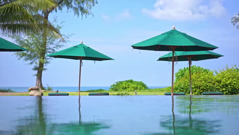 sea view resort with infinity pool and green sun umbrellas