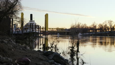 A-large-steamboat-sits-in-a-dock-on-a-bank-in-the-Sacramento-River-at-sunset