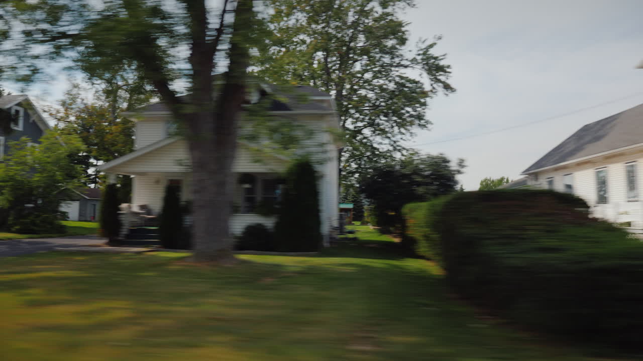 paseo a lo largo de los típicos suburbios americanos vista desde la ventana del coche - visibles casas de madera blanca y