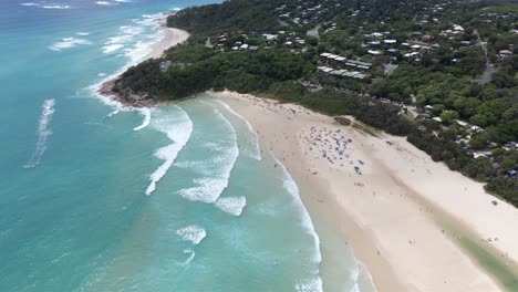 tourists swim turquoise blue sea at cylinder beach in summer - cylinder headland foreshore in point lookout, north stradbroke island, qld, australia