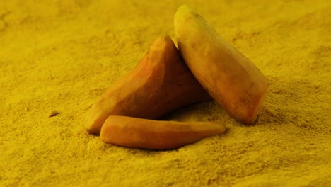 cúrcuma o cúrcuma descascarada entera en un lecho de la misma especia molida