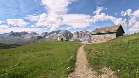 approaching a white chapel and mountain cabin a green summer meadow