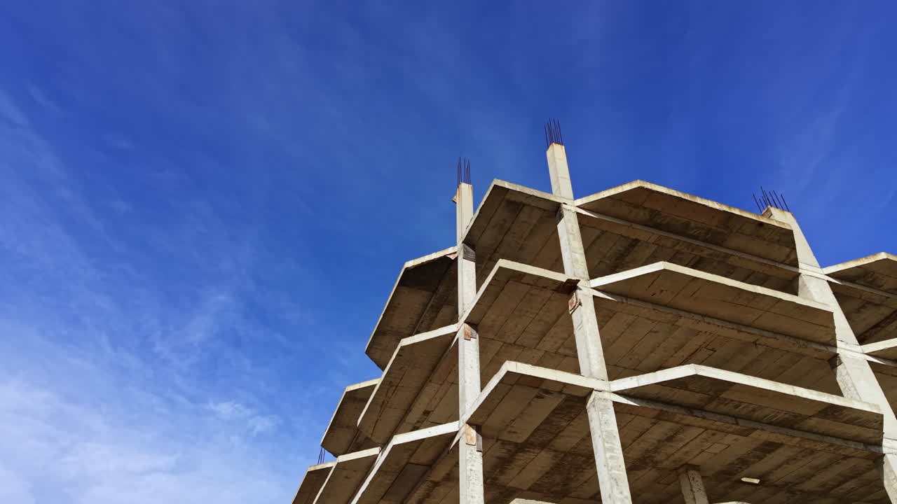 Il degrado urbano dipinge una scena vivida sotto il vasto cielo blu, mentre una fatiscente struttura di cemento si protende verso il cielo nel cuore della città.