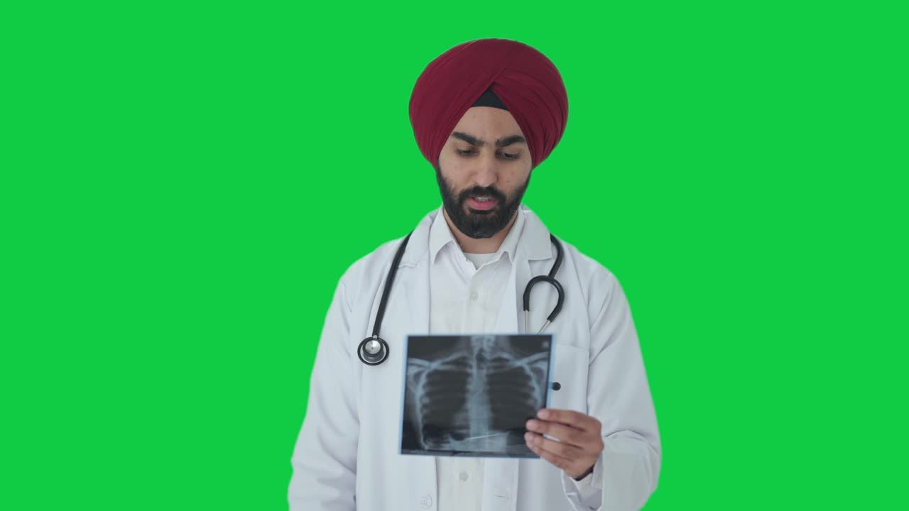 Serious Sikh Indian doctor checking X ray report Green screen