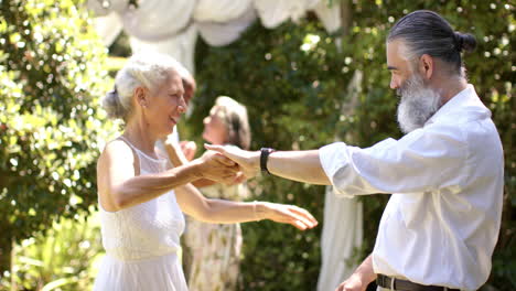 dancing together, senior bride and groom enjoying outdoor wedding event with friends in background