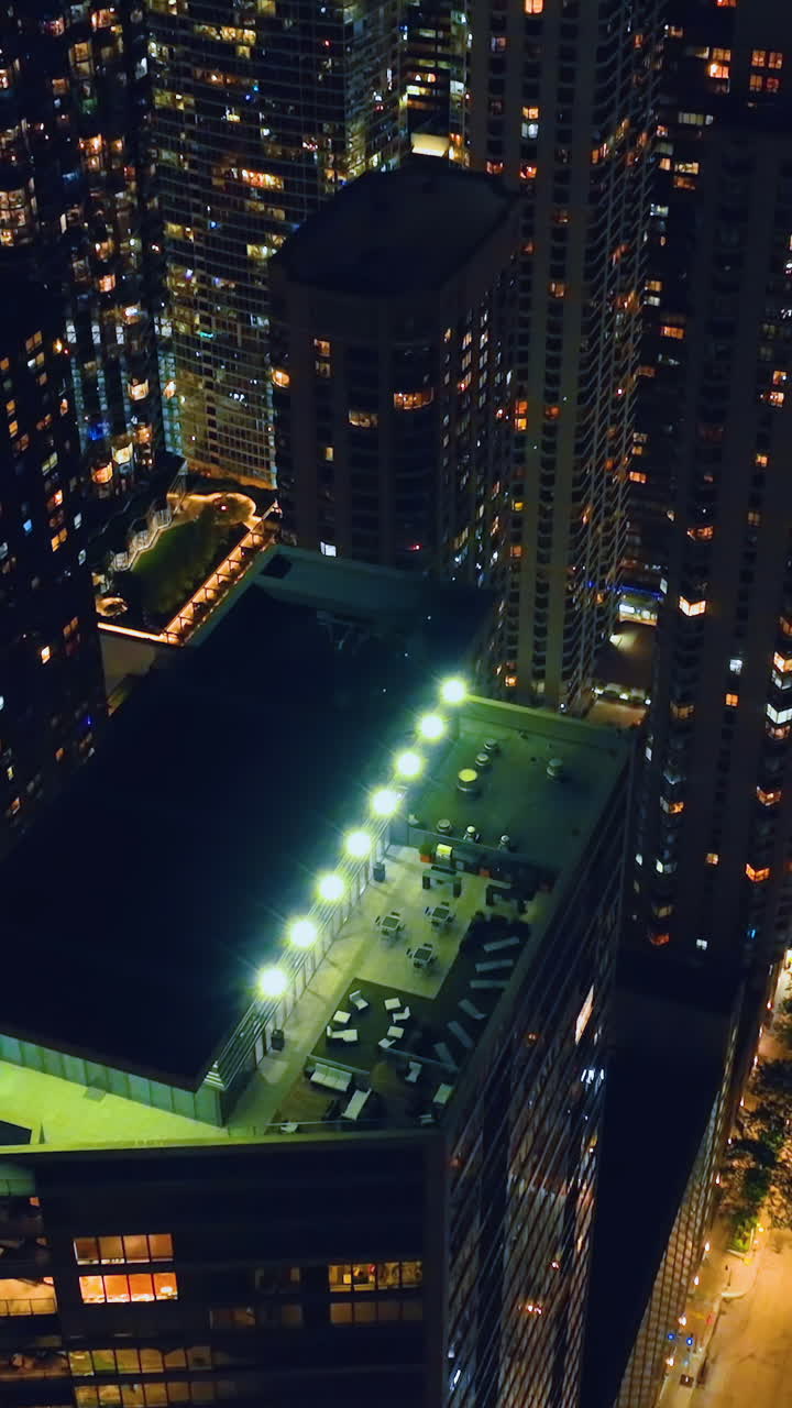 Night city of Chicago with illumination. Aerial view of the roofs of skyscrapers with a terrace. Street lighting. Vertical video