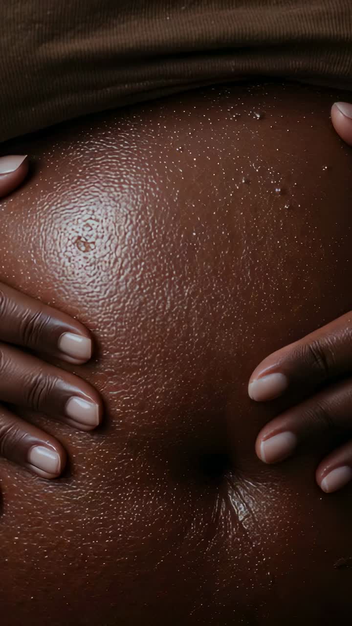 Vertical video: Withdrawing woman's hands from dark abdomen on bed, revealing navel and brown top