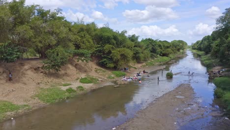 Haitianische-Frauen-Und-Ihre-Kinder-Waschen-Kleidung-Und-Baden-Im-Massakerfluss-In-Dajabon,-Grenze-Zwischen-Haiti-Und-Der-Dominikanischen-Republik