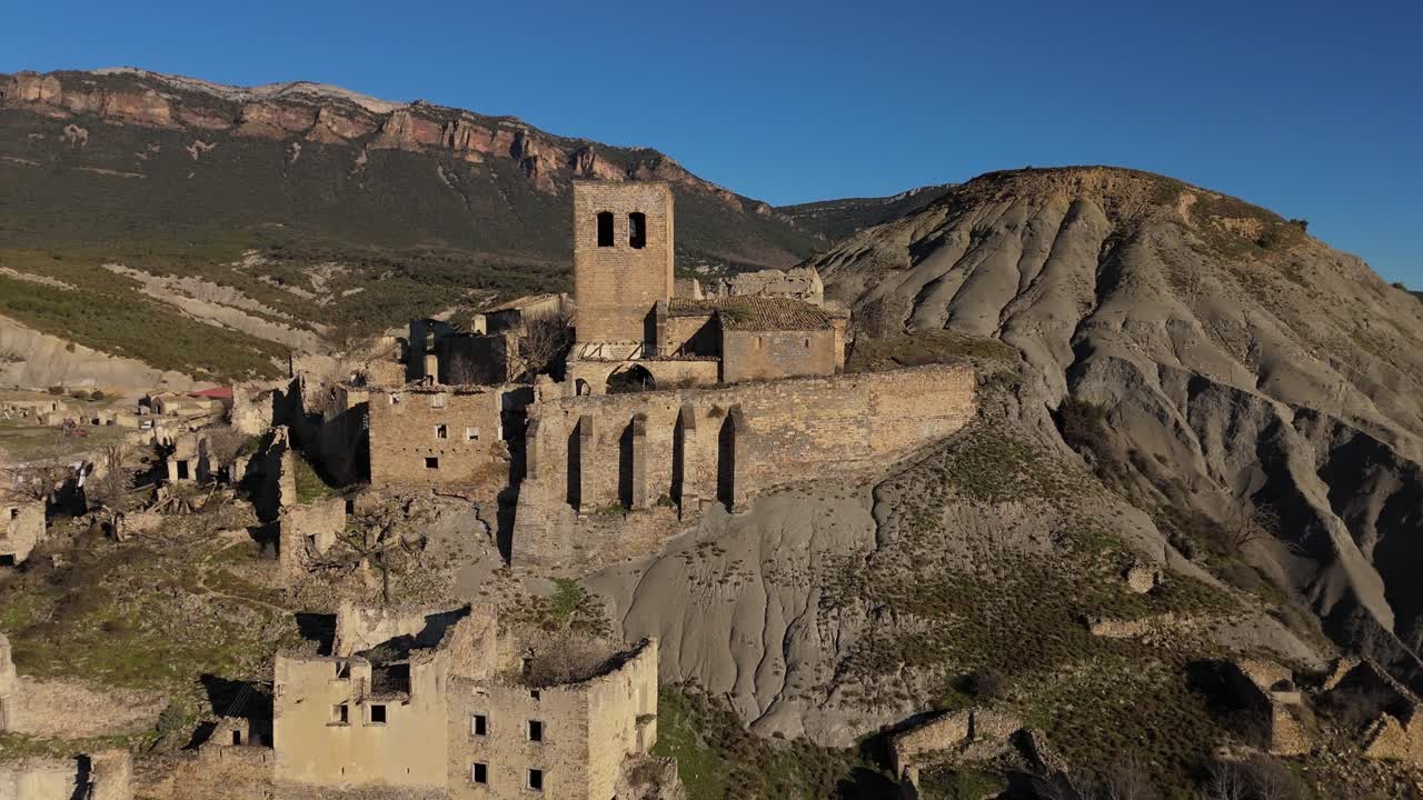 Orbiting drone movement the church of the abandoned village of Esc&oacute;, Spain and the mountains as a background