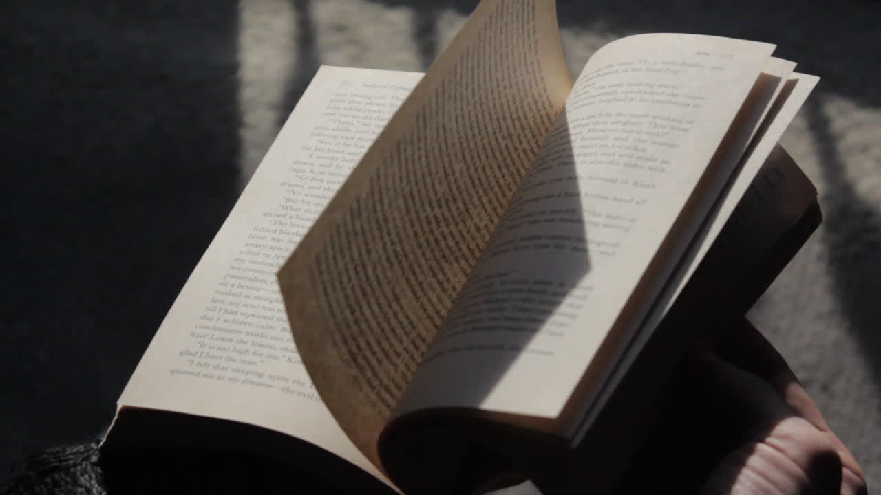 중간 거리에서 날카로운 초점으로 온화하고 몽환적인 톤으로 책 페이지를 빠르게 뒤집습니다.