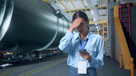 asian business woman not satisfied and shakes her head while using mobile phone in pipe manufacturing factory