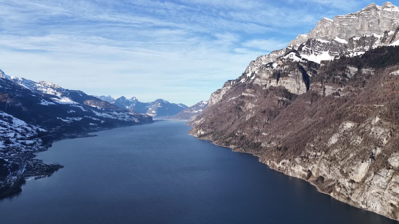 Walensee, jota kehystävät jyrkät Alppien kalliot ja lumihuippuiset vuoret, kirkkaan sinisen taivaan alla. Walenstadt, Sveitsi.