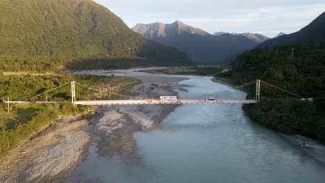 vehicles crossing steel bridge over glacial river