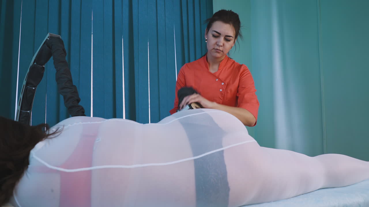 평온 한 여자 는 여자 에게 전문적 인 진공 롤러 마사지 를 한다