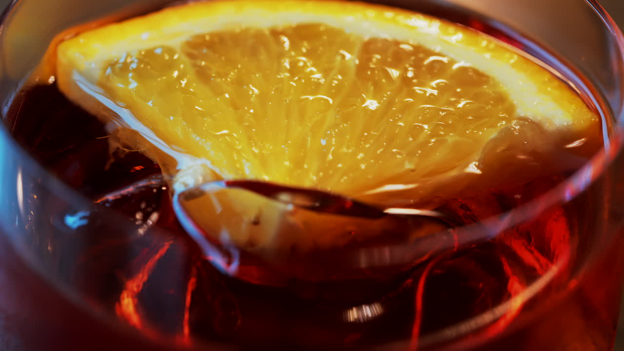 Primo piano di un cocktail Negroni con fetta d'arancia e cubetti di ghiaccio su un tavolo di legno