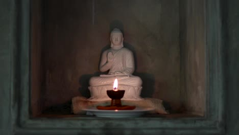 Still-shot-of-Buddha-statue-with-candle-in-front-of-it