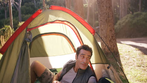 man lying in tent and having coffee