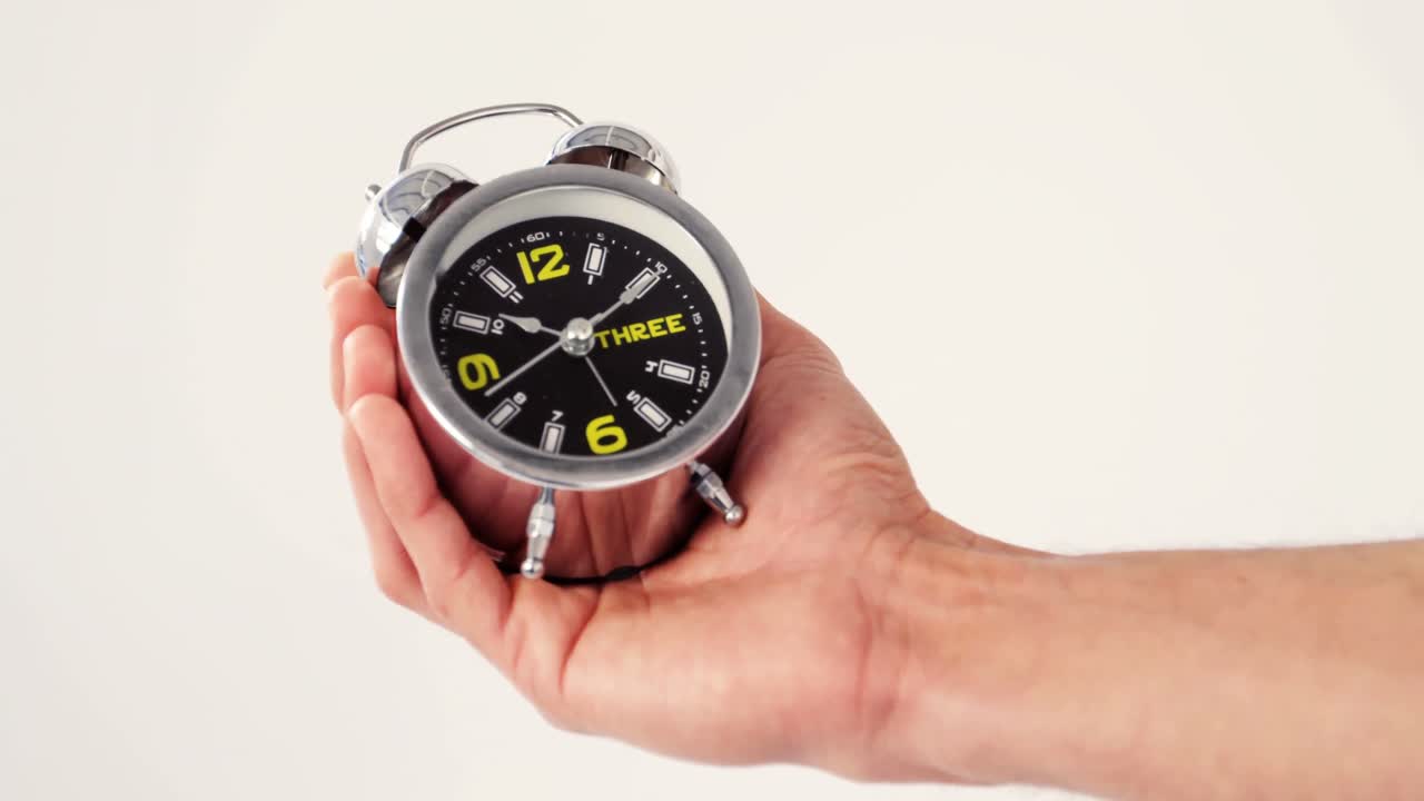 hombre con la mano en el reloj despertador